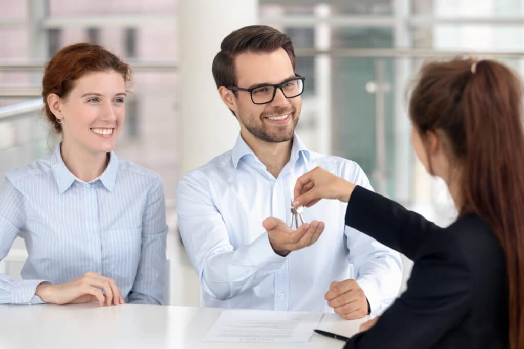 woman giving the buyers the key to the insurance business consulting office