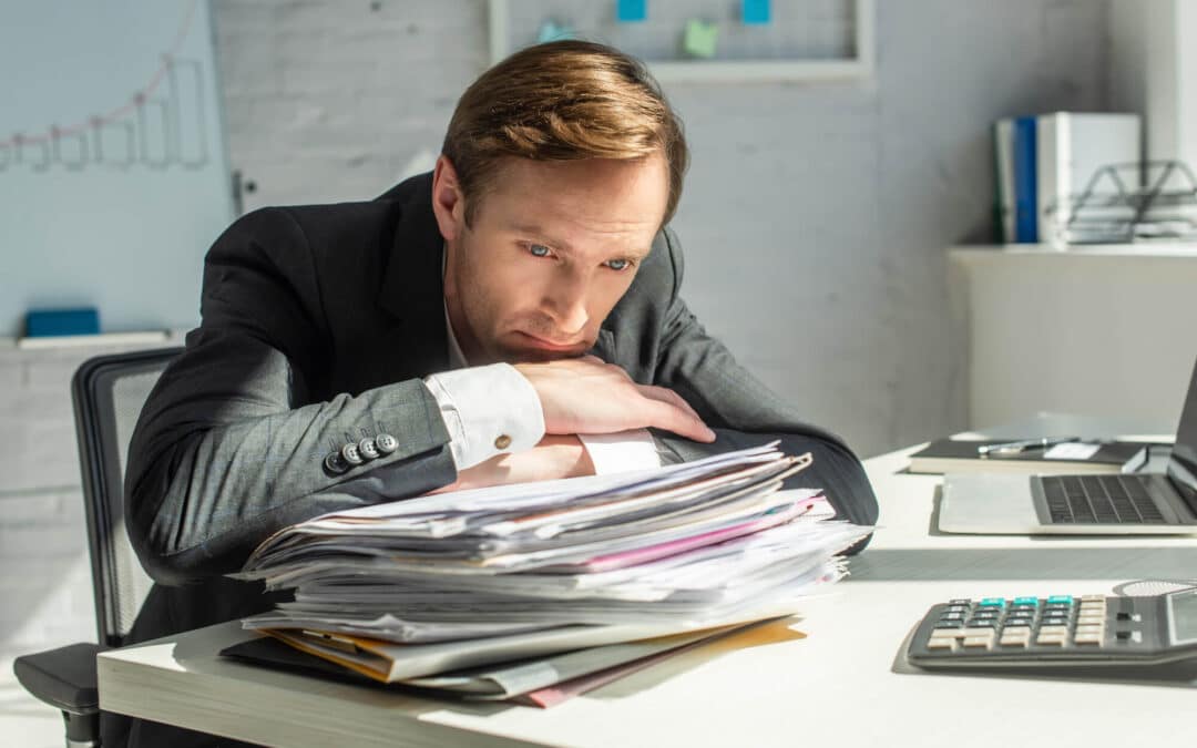 business person leaning over a pile of documents after buying an insurance agency